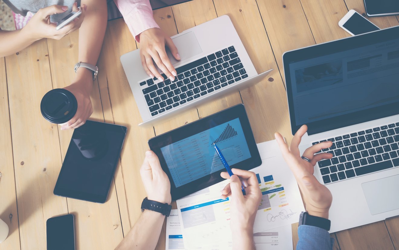 Generische Büro Szene Generisches Büro, mehrere Hände die über einen Tisch greifen Laptops und Tablets auf dem tisch